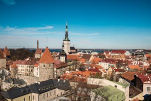 Discover the charming medieval skyline of Tallinn, Estonia, with iconic red rooftops under a clear blue sky.