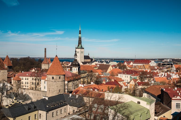 Discover the charming medieval skyline of Tallinn, Estonia, with iconic red rooftops under a clear blue sky.