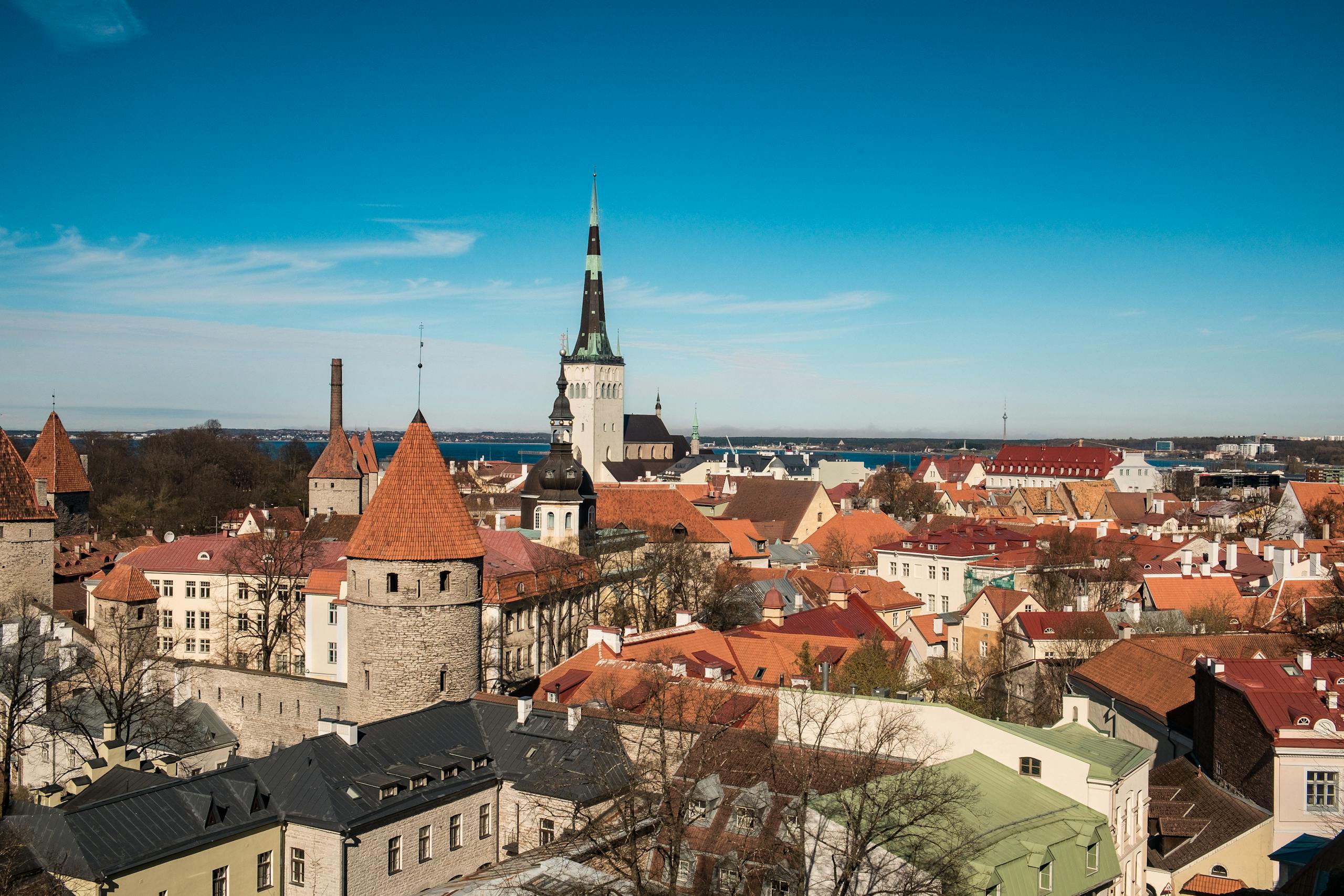 Discover the charming medieval skyline of Tallinn, Estonia, with iconic red rooftops under a clear blue sky.